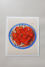 Art print of a vibrant bowl of red cherries with stems, arranged in a decorative blue-rimmed bowl with floral patterns — printed on textured fine art paper and photographed in natural light