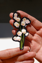Cute lily of the valley flower vinyl sticker with hidden cute cartoon bunnies, glossy die-cut design, held in hand under natural sunlight — aesthetic floral stationery for water bottles, laptops, or journals